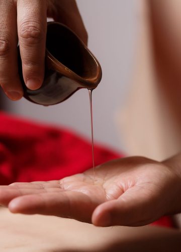 close-up of the masseur's hands, a drop of massage oil flows dow