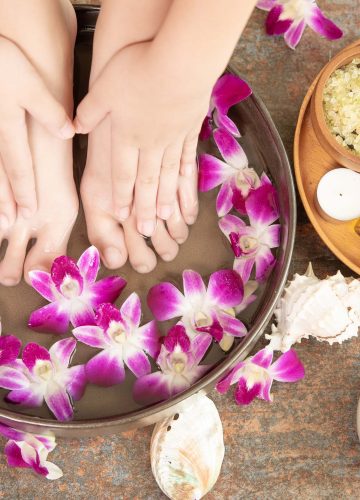 closeup view of woman soaking her hand and feet in dish with wat